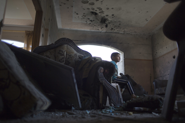 Palestinian boy sits in the living room of his family house following Israeli artillery shelling in town of Beit Hanoun in the northern Gaza Strip on Tuesday (AP photo)
